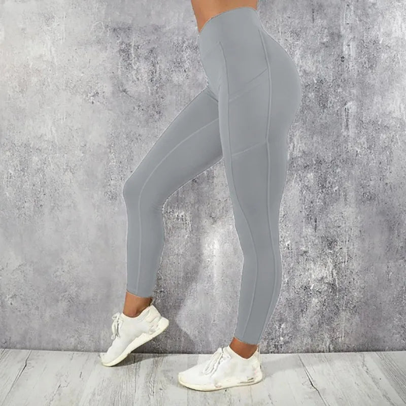 Person wearing gray leggings and white sneakers against a concrete wall.