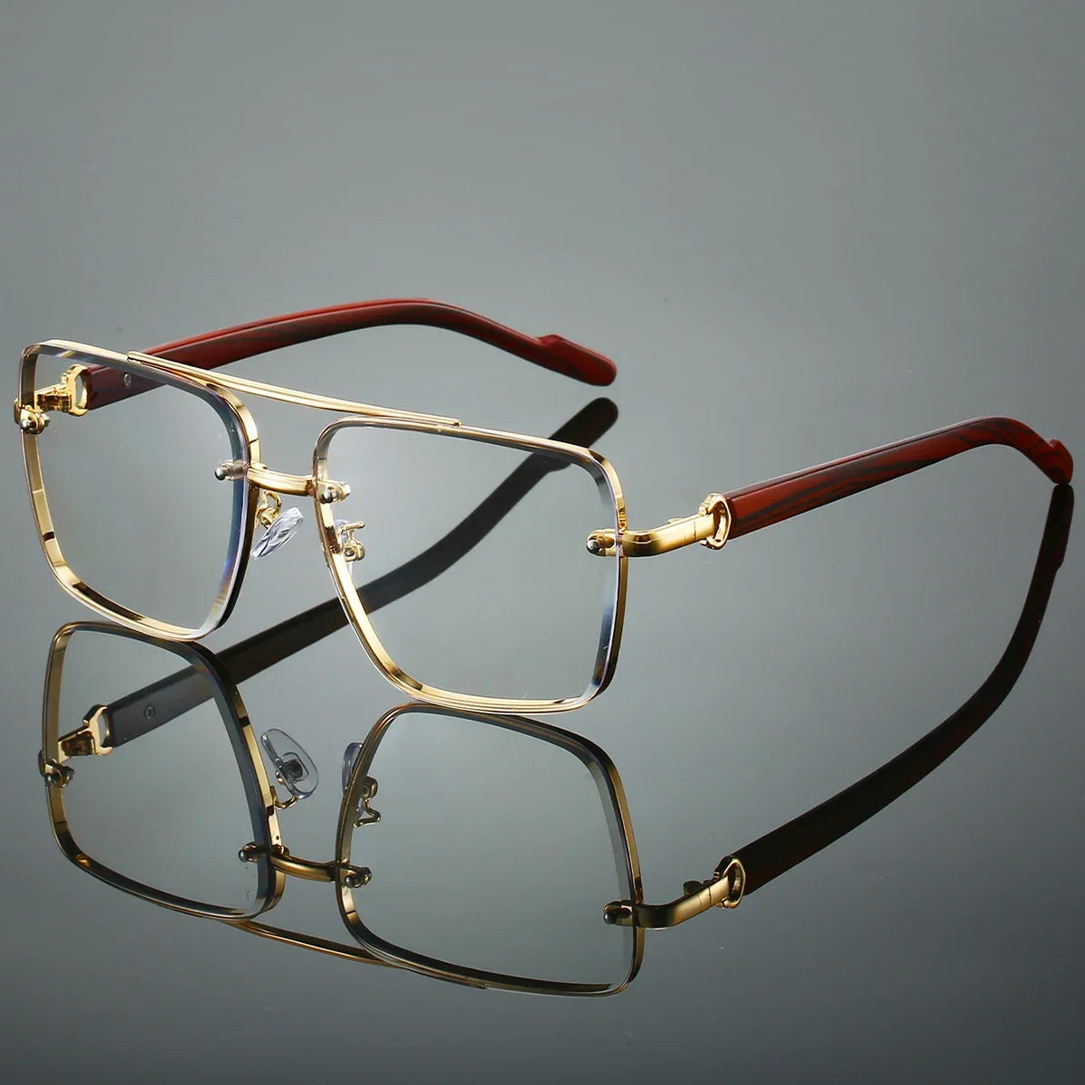 Gold-framed eyeglasses with red arms on a reflective surface