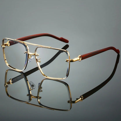 Gold-framed eyeglasses with red arms on a reflective surface
