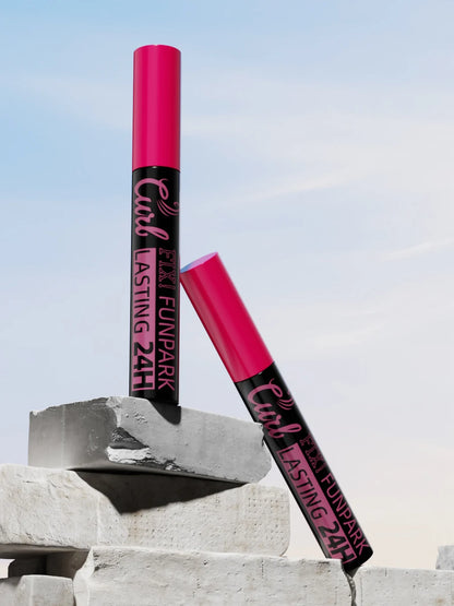 Two pink lip products with black text on a concrete surface against a blue sky.