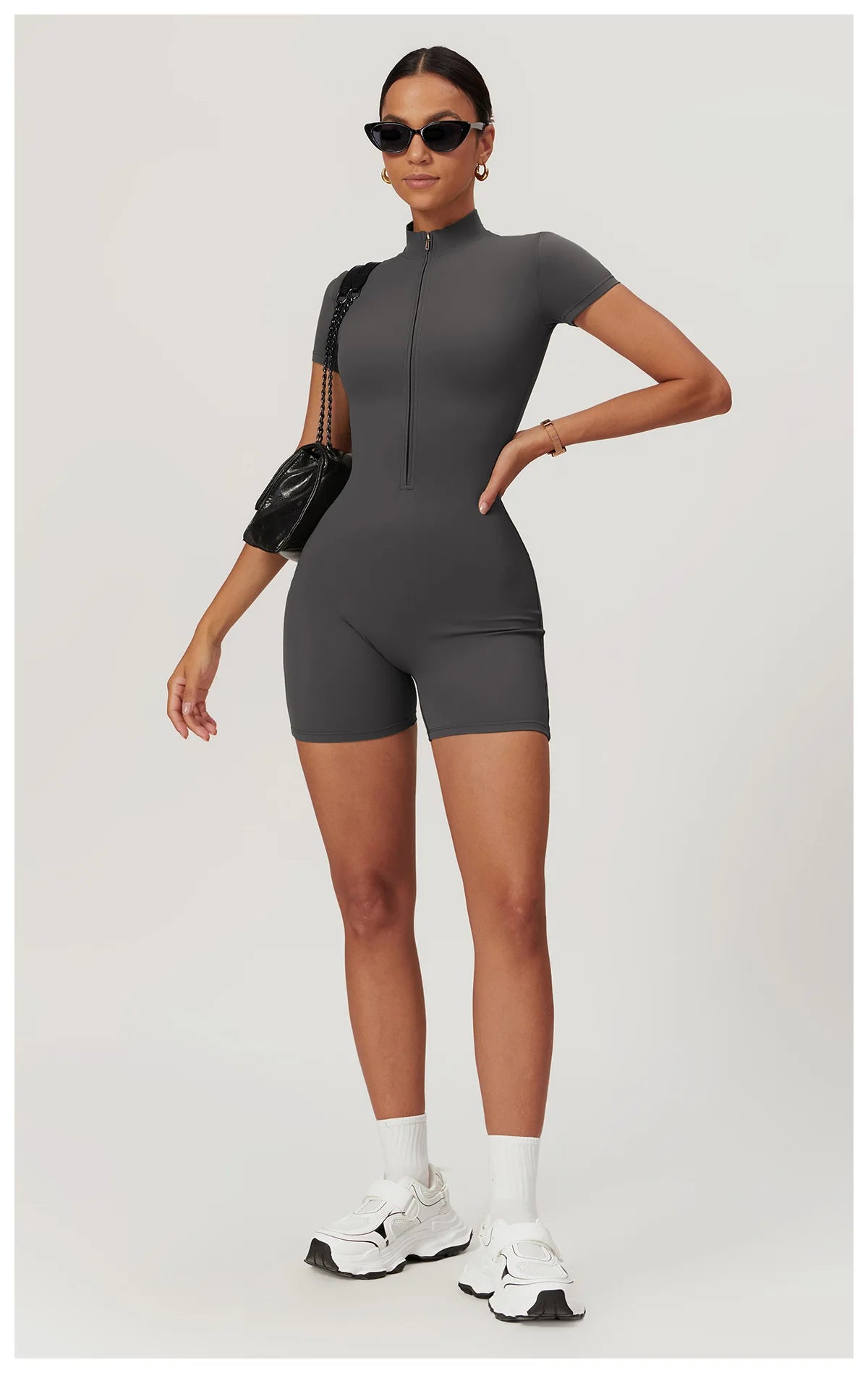 Woman wearing a gray bodysuit with black sleeves on a white background
