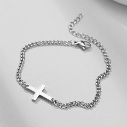 Silver chain bracelet with a cross pendant on a light gray background