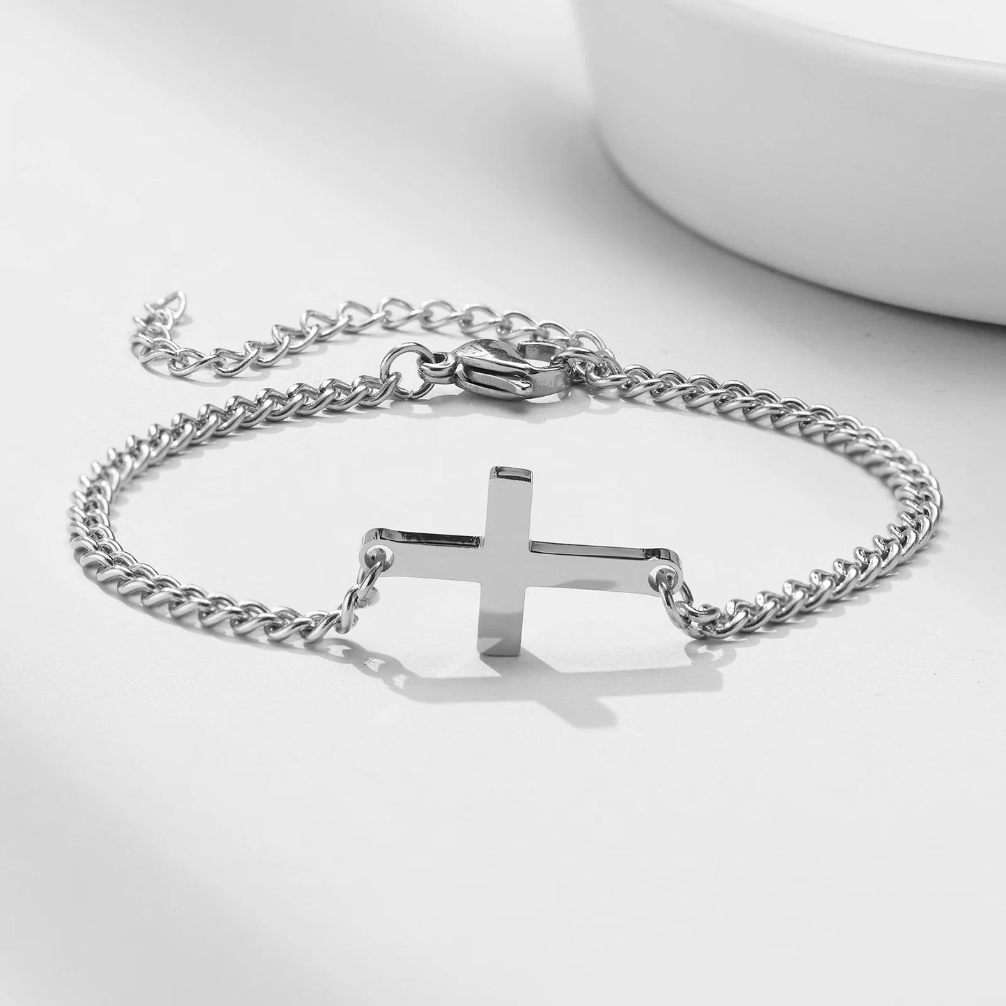 Silver chain bracelet with a cross pendant on a white background