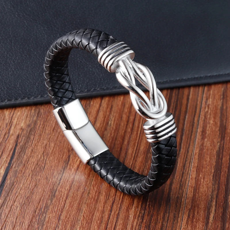 Black braided leather keychain with silver metal design on a wooden surface