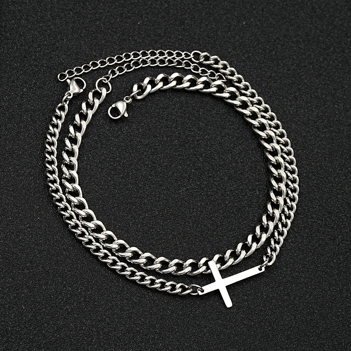Silver chain necklace with a cross pendant on a black background