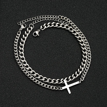 Silver chain necklace with a cross pendant on a black background