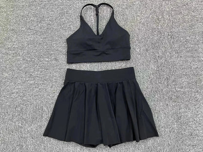 Black sports bra and skirt set on a textured gray surface