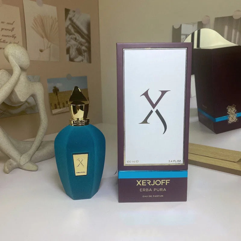 Xerjoff Erba Pura perfume bottle and packaging on a surface with decorative items in the background.