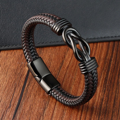 Brown braided leather bracelet with metal clasp on a wooden surface