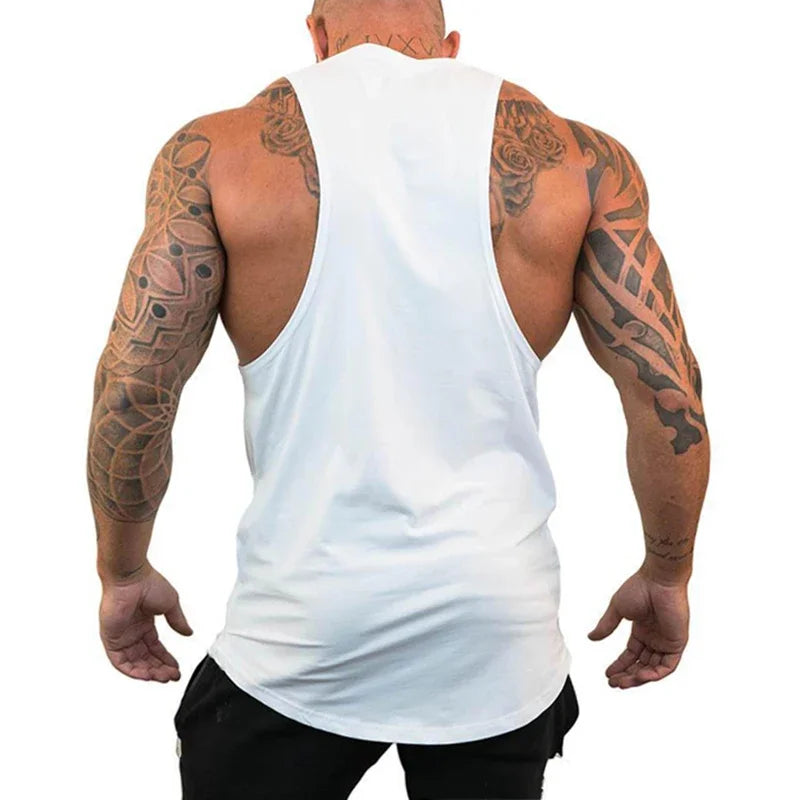 Man wearing a white tank top with visible tattoos on arms and back.
