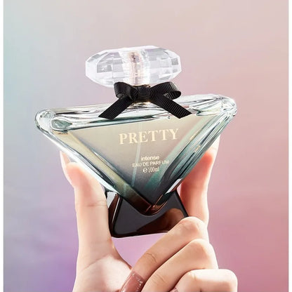 Hand holding a perfume bottle labeled 'Pretty' against a gradient background