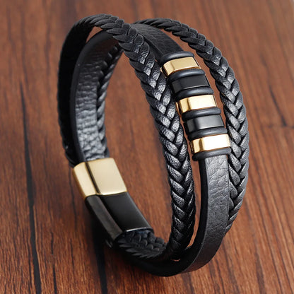 Black braided leather bracelet with gold accents on a wooden surface