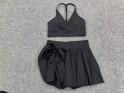 Black sports bra and skirt set on a textured gray surface
