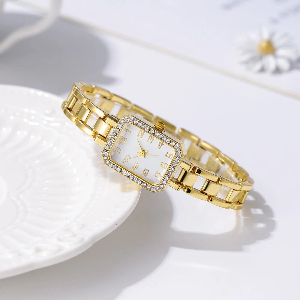 Gold wristwatch with a square face on a white surface