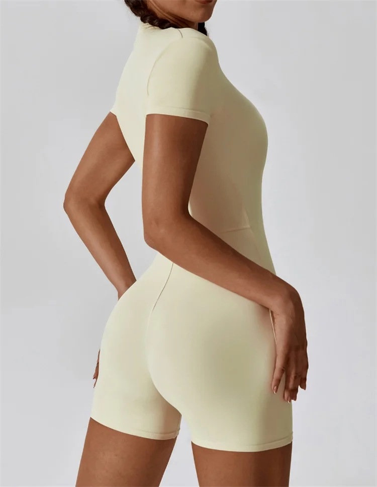 Person wearing a light yellow bodysuit against a plain background