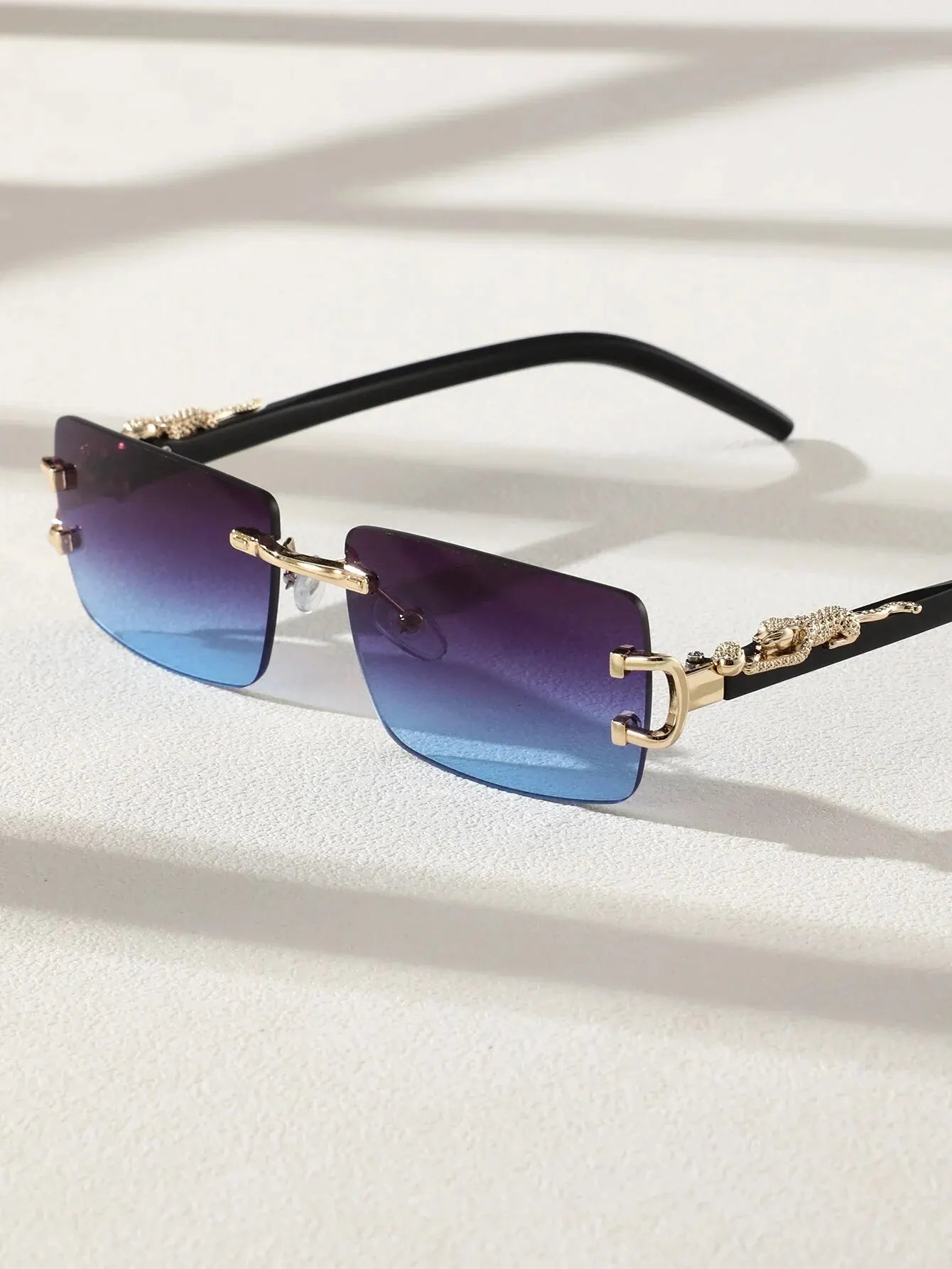 Sunglasses with gradient blue lenses and gold frames on a light background