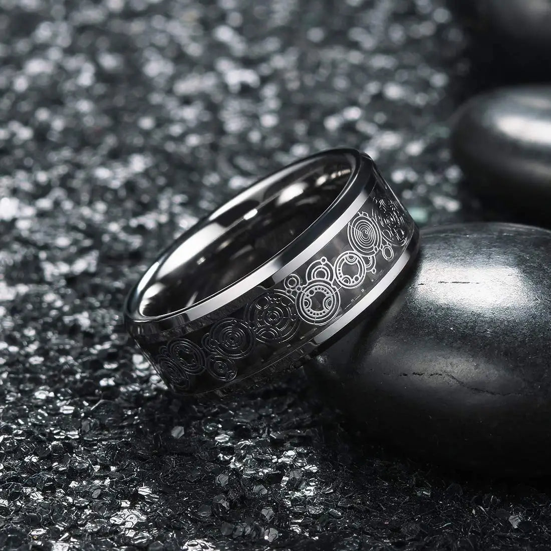 Black tungsten ring with engraved design on a dark textured surface