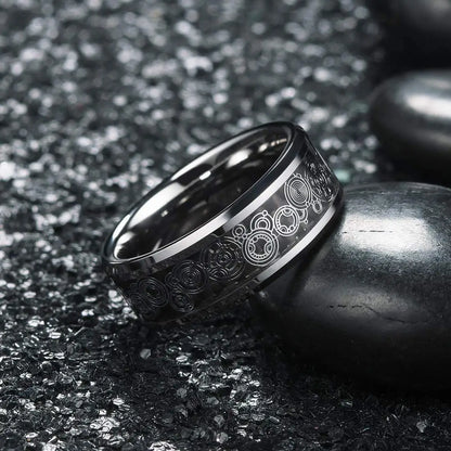 Black tungsten ring with engraved design on a dark textured surface