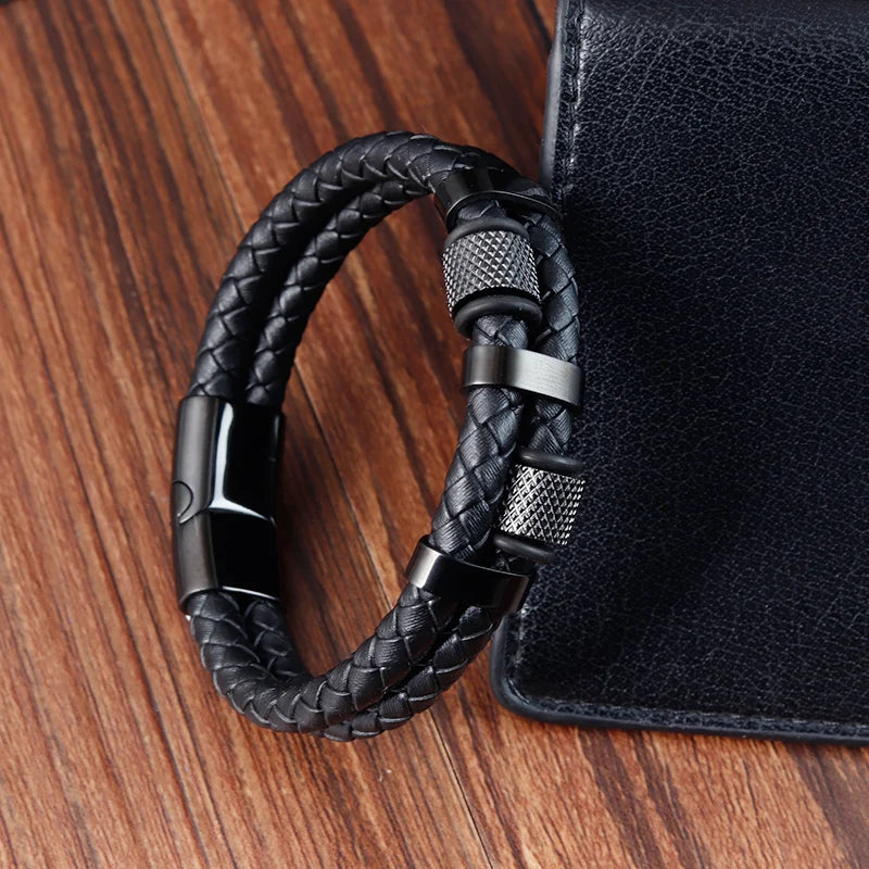 Black braided keychain attached to a black leather bag on a wooden surface