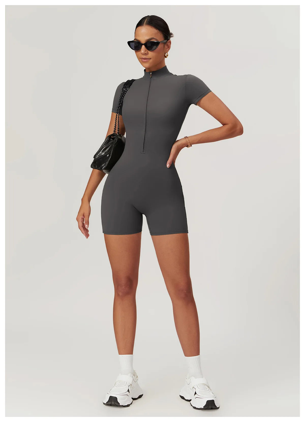 Woman wearing a gray bodysuit with a plain background