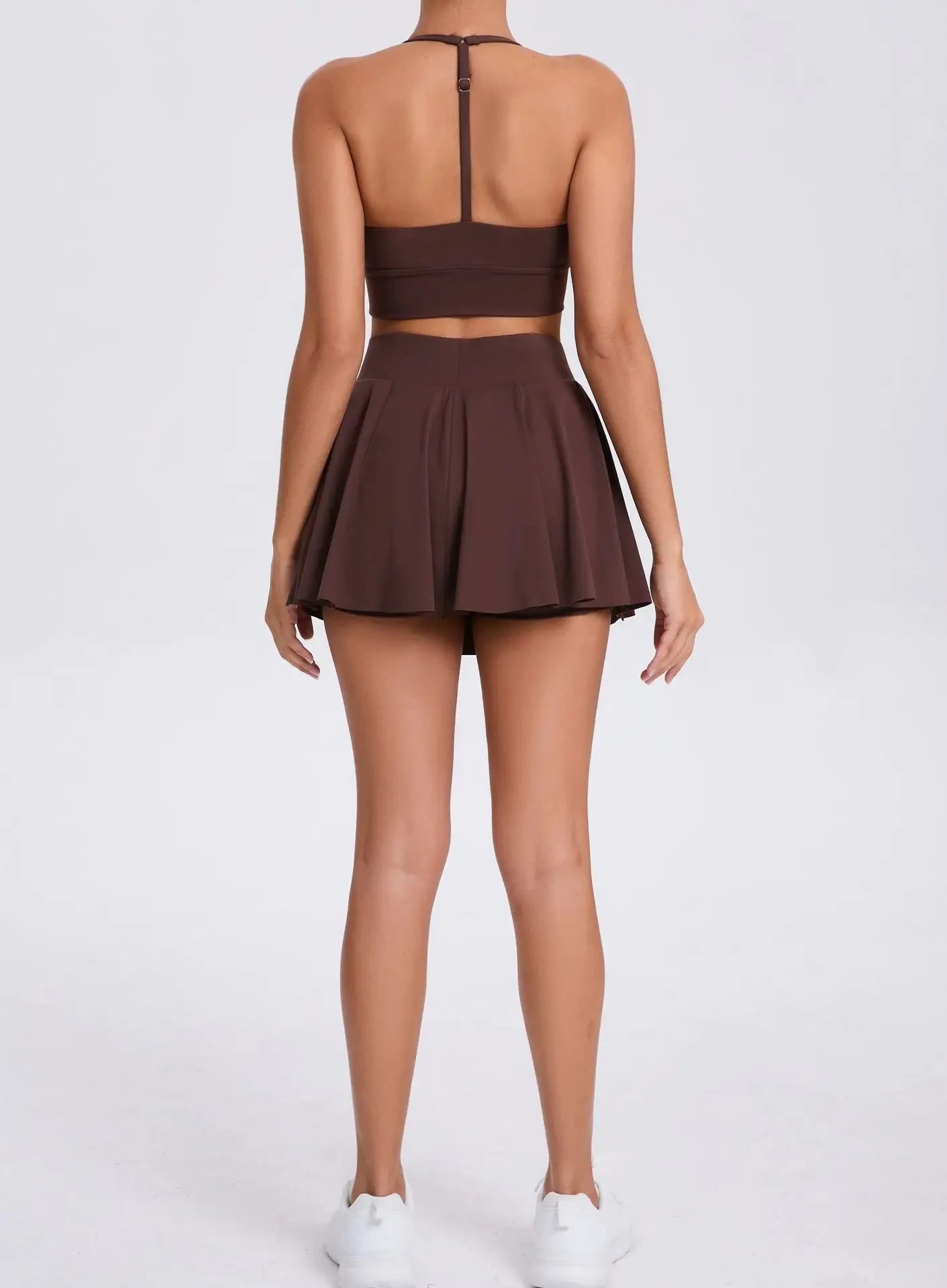 Brown two-piece outfit with a crop top and pleated skirt on a white background