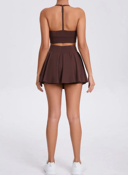 Brown two-piece outfit with a crop top and pleated skirt on a white background