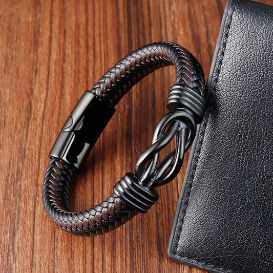 Brown braided leather bracelet with black clasp on a wooden surface