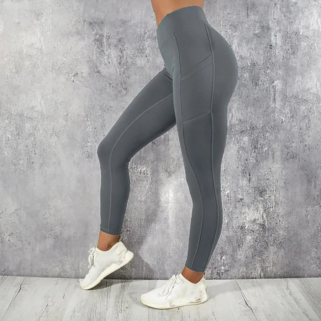 Person wearing gray leggings and white sneakers against a concrete wall.