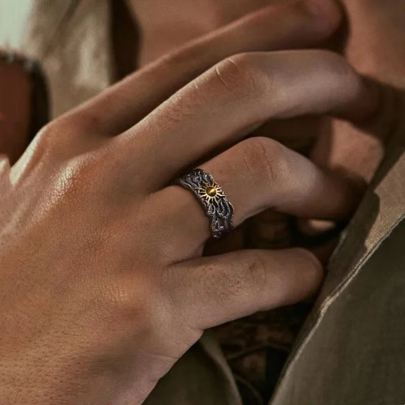Close-up of a hand wearing a decorative ring with a sun design.