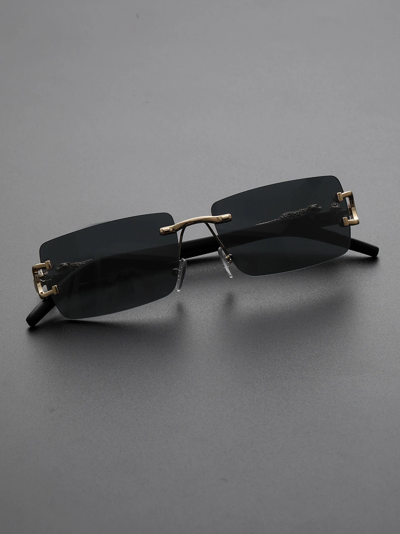 Black sunglasses with gold accents on a gray background