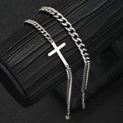 Silver chain bracelet with a cross pendant on a dark textured surface