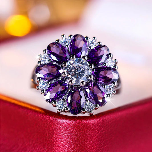 Purple gemstone ring with silver accents on a red surface