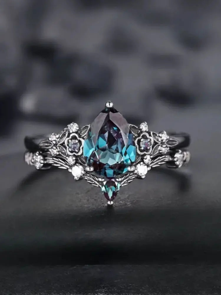 Elegant ring with a teardrop-shaped gemstone on a dark background