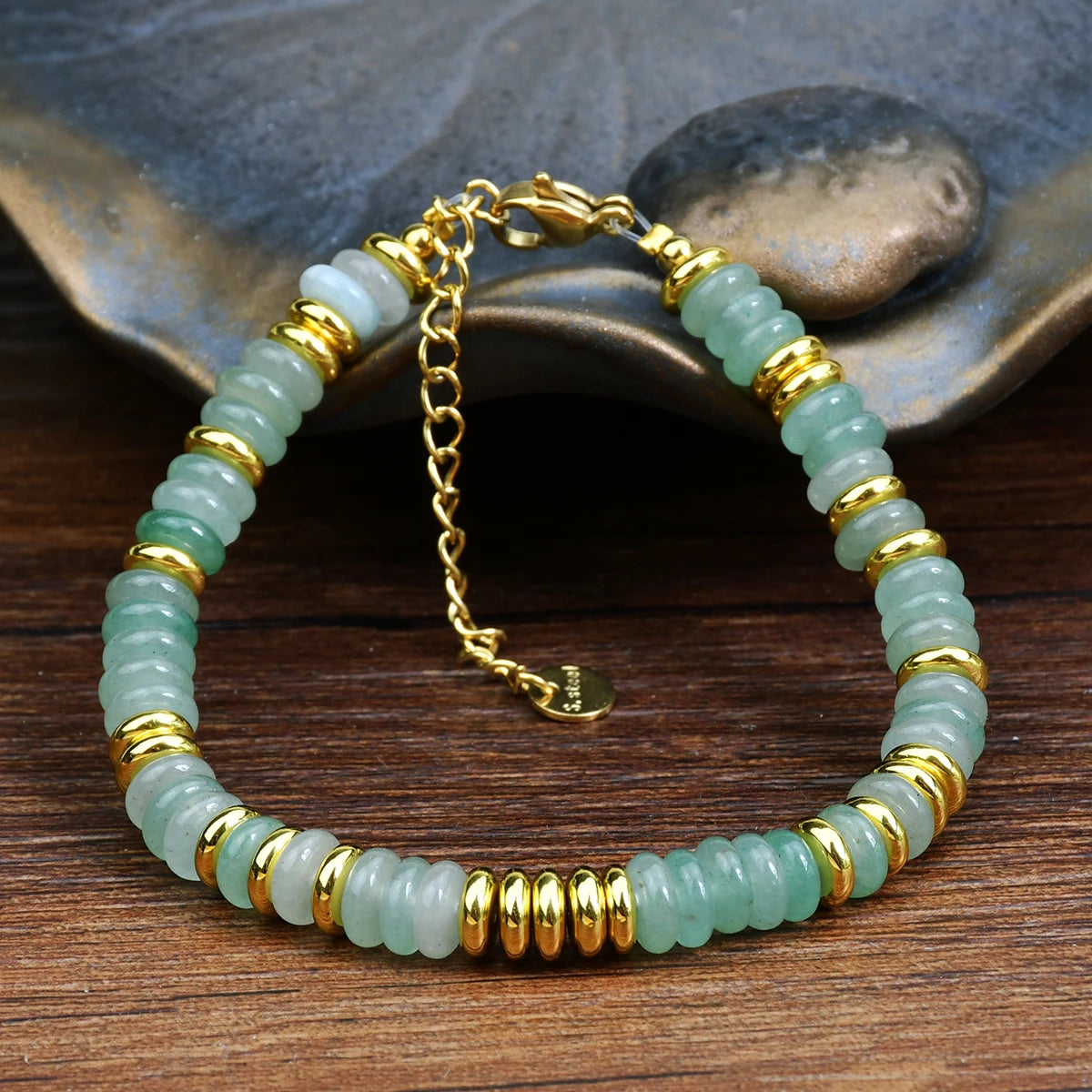 Bracelet with green beads and gold accents on a wooden surface