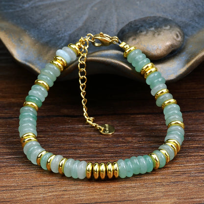 Bracelet with green beads and gold accents on a wooden surface