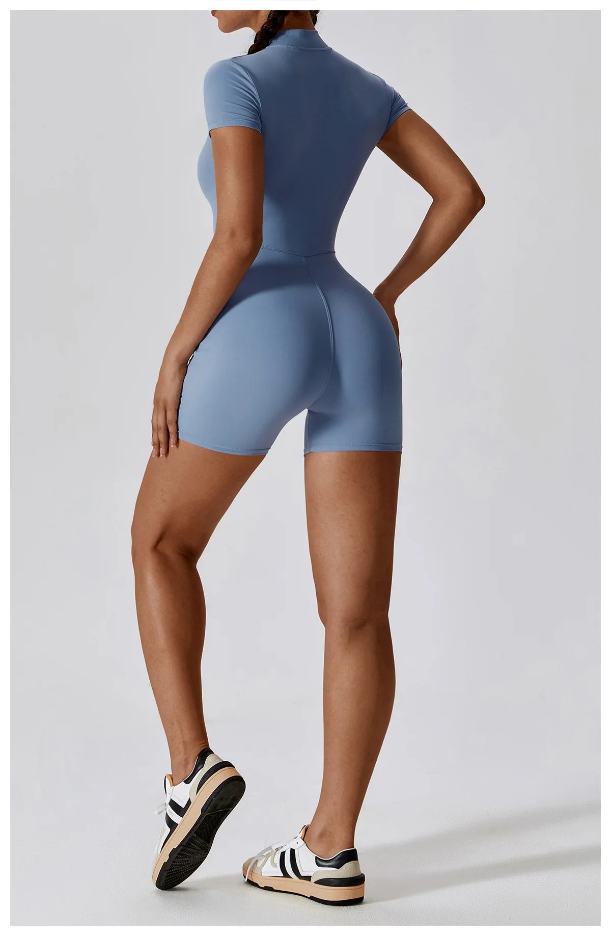Person wearing a blue bodysuit on a light gray background