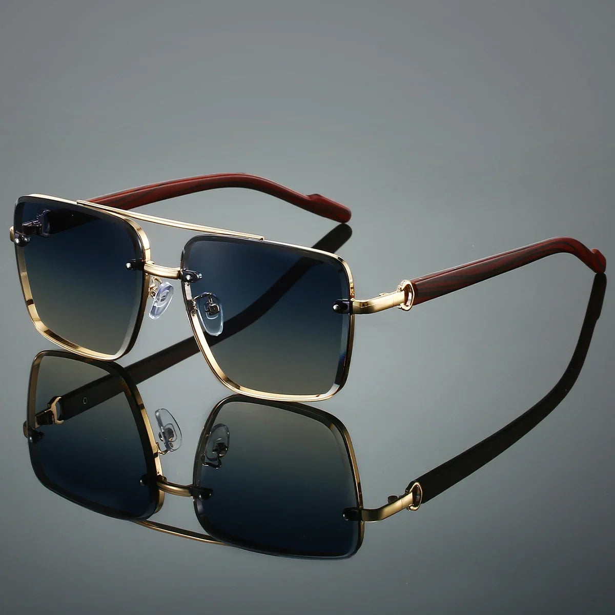 Sunglasses with gold frame and brown arms on a reflective surface with a gray background