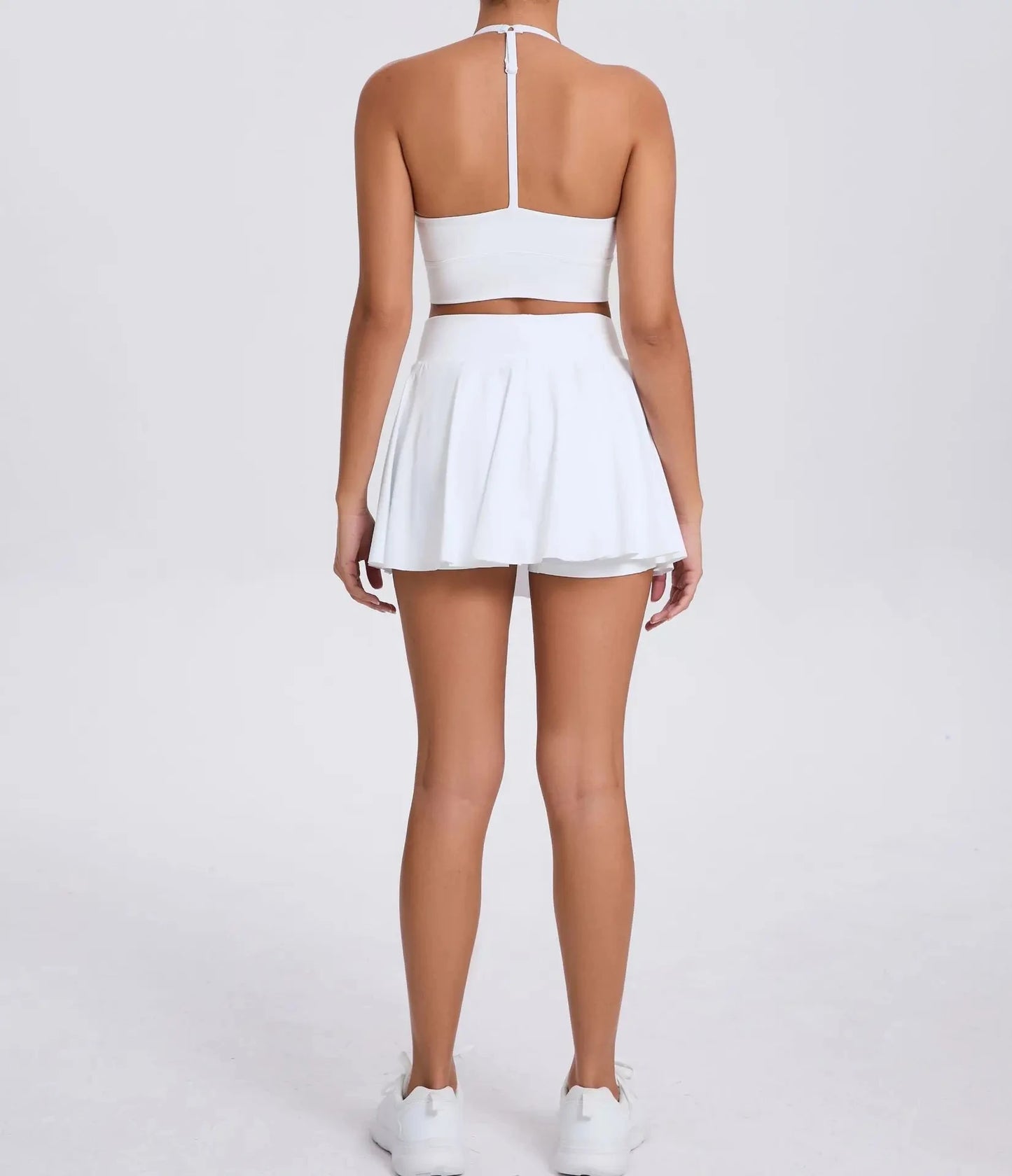 Person wearing a white outfit with a skirt on a plain background