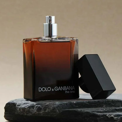 Perfume bottle with black cap on a stone surface against a beige background