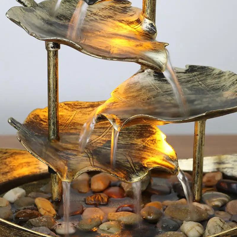 Decorative water fountain with leaf-shaped tiers on a pebble bed