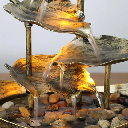 Decorative water fountain with leaf-shaped tiers on a pebble bed