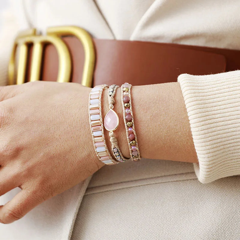 Close-up of a wrist wearing multiple beaded bracelets with a neutral background