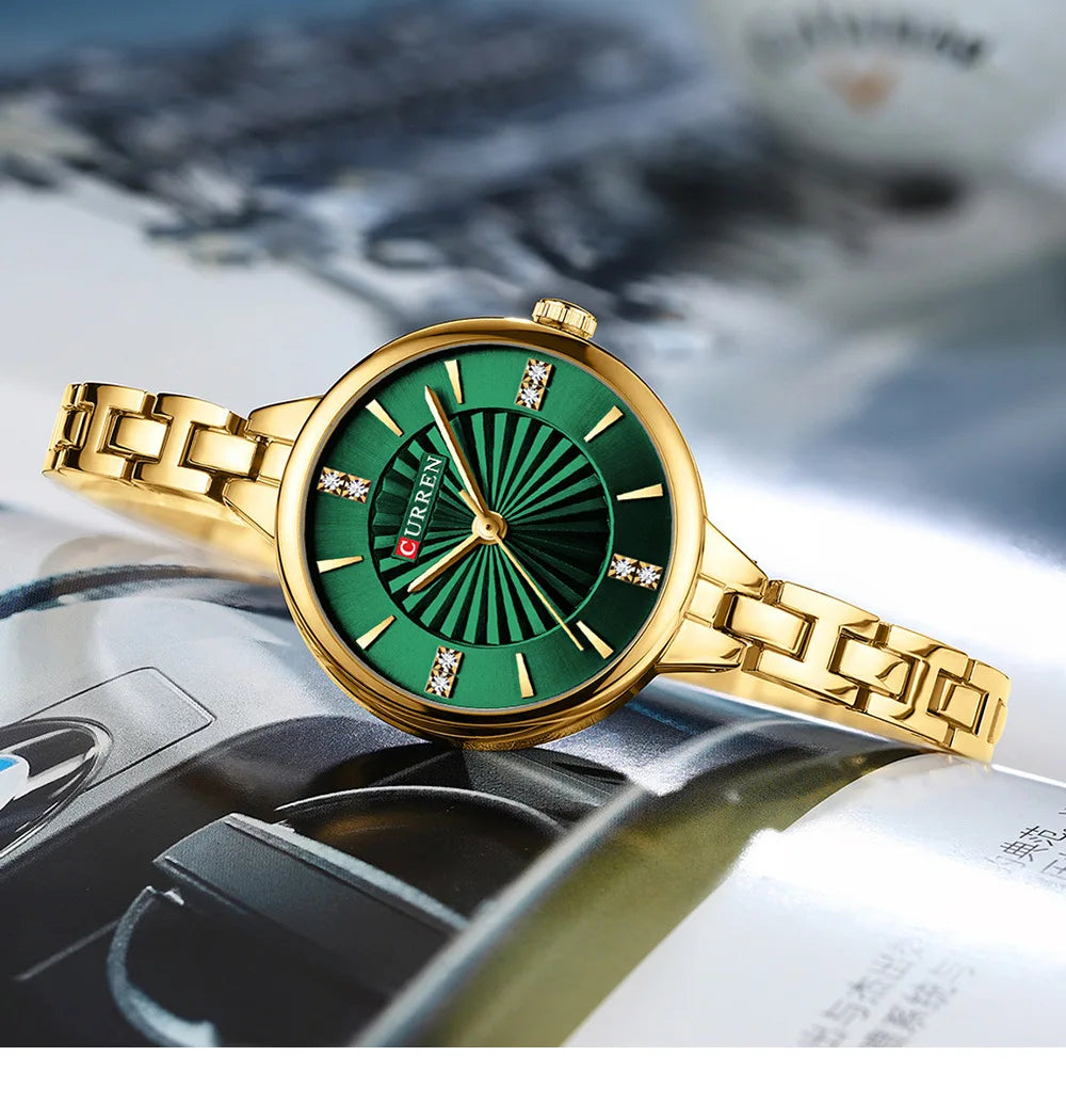 Gold watch with a green face on a metallic surface