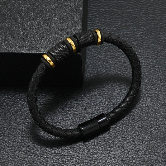Black braided bracelet with gold accents on a textured black background