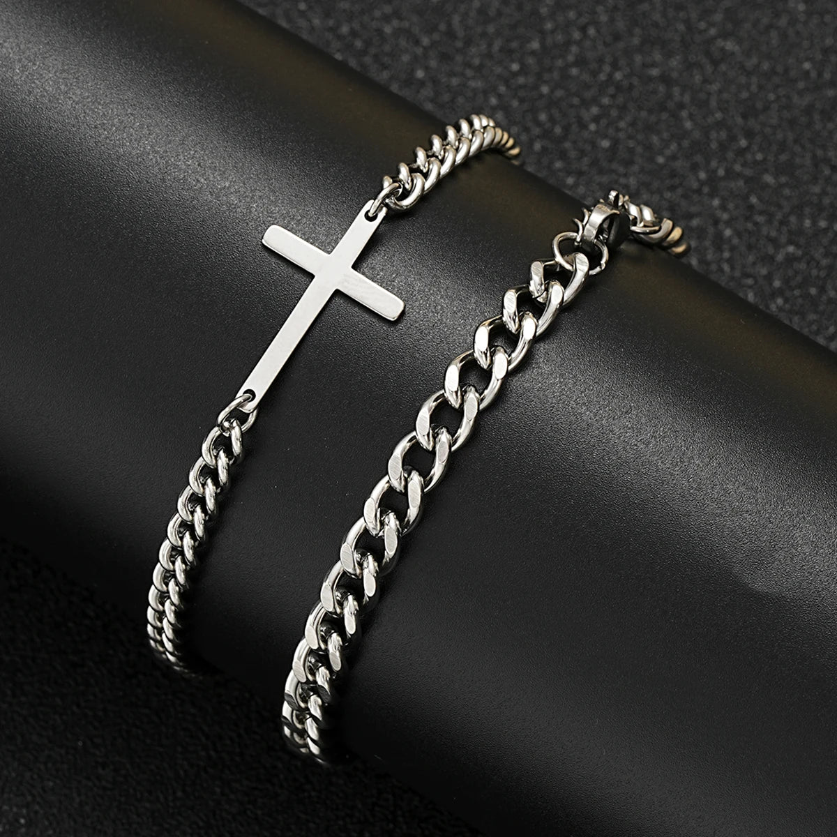 Silver chain bracelet with a cross pendant on a dark surface