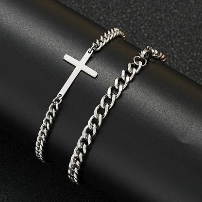 Silver chain bracelet with a cross pendant on a dark surface