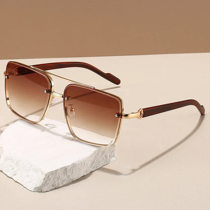 Sunglasses with brown gradient lenses and gold frames on a beige surface