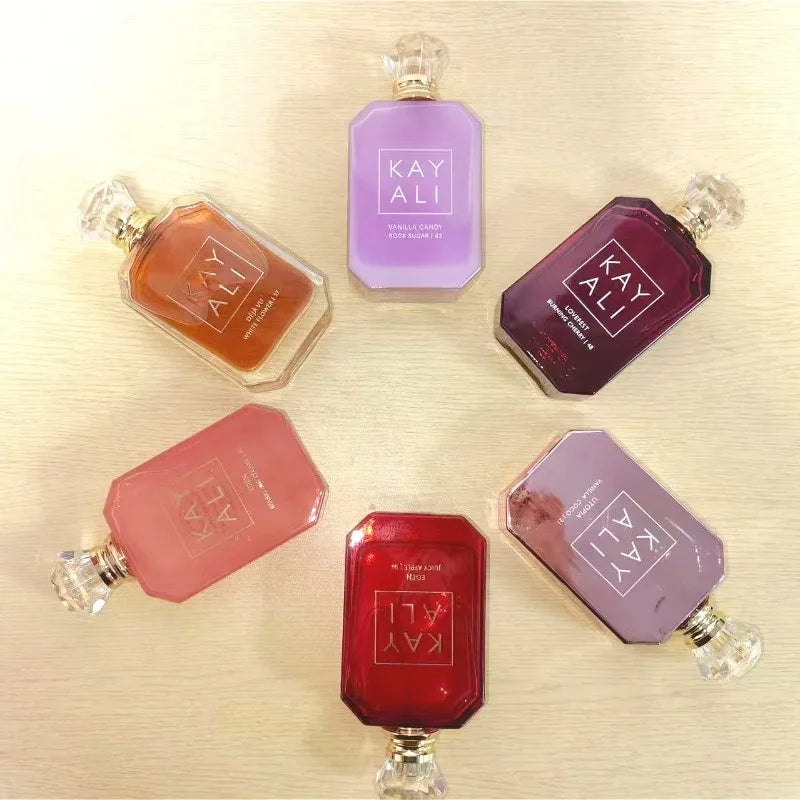 Collection of Kay Ali perfume bottles in various colors on a light wooden surface.