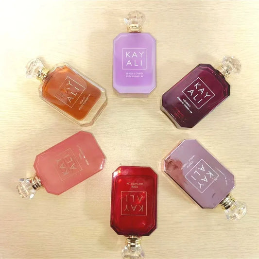 Collection of Kay Ali perfume bottles in various colors on a light wooden surface.