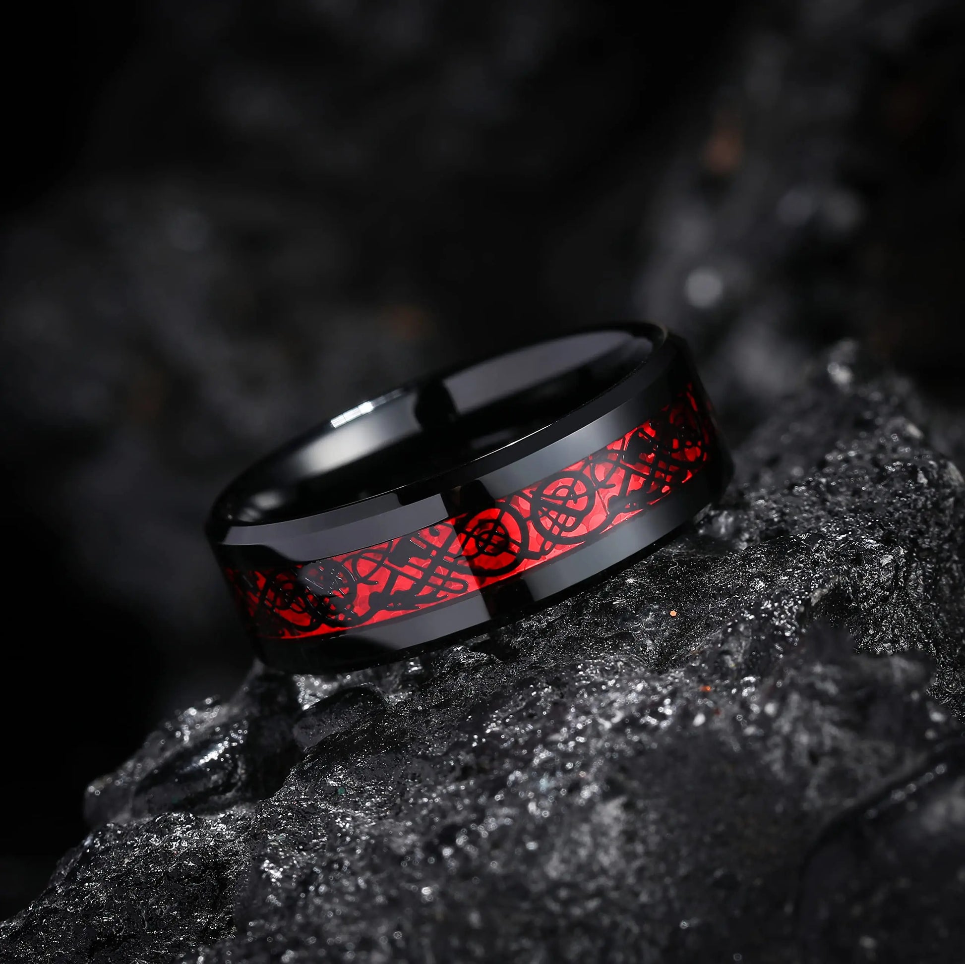 Black ring with red floral design on a dark textured surface